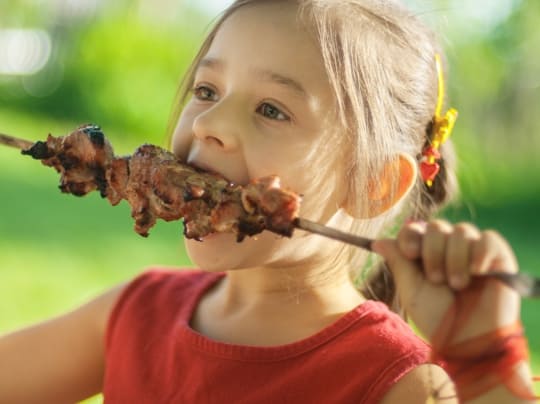 girl eating meat skewer
